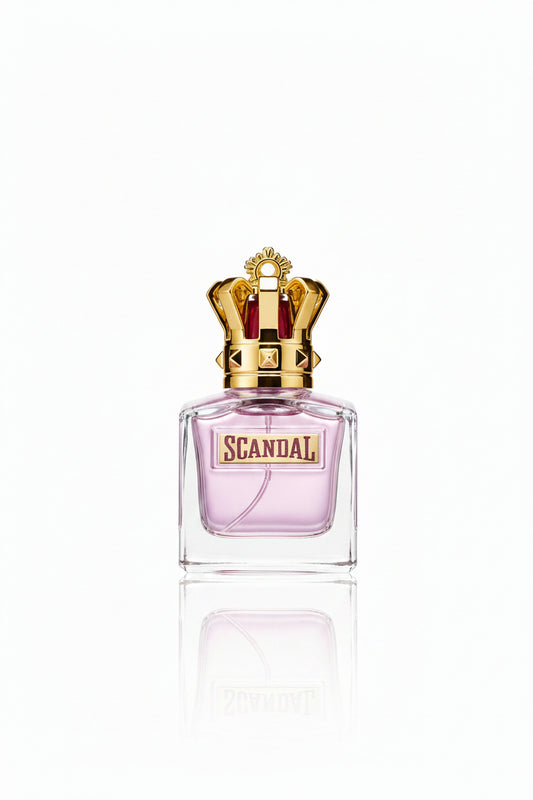 A hand with black fingernails holds a bottle of Scandal perfume by Cartier, which features a clear glass body with pink liquid and a prominent gold crown cap. Other identical perfume bottles are lined up in the background on a gold and white display stand.