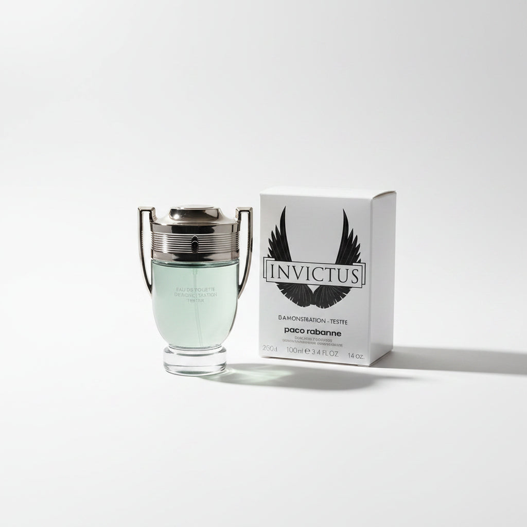 Paco Rabanne Invictus Eau de Toilette demonstration tester bottle with a silver-toned winged cap, shown next to its white box featuring a black wing logo, set outdoors on a weathered wooden surface with blurred green foliage in the background.