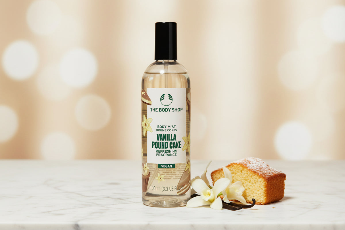 A bottle of The Body Shop Vanilla Pound Cake Refreshing Fragrance body mist, placed on a wooden table with a blurred bathroom background.